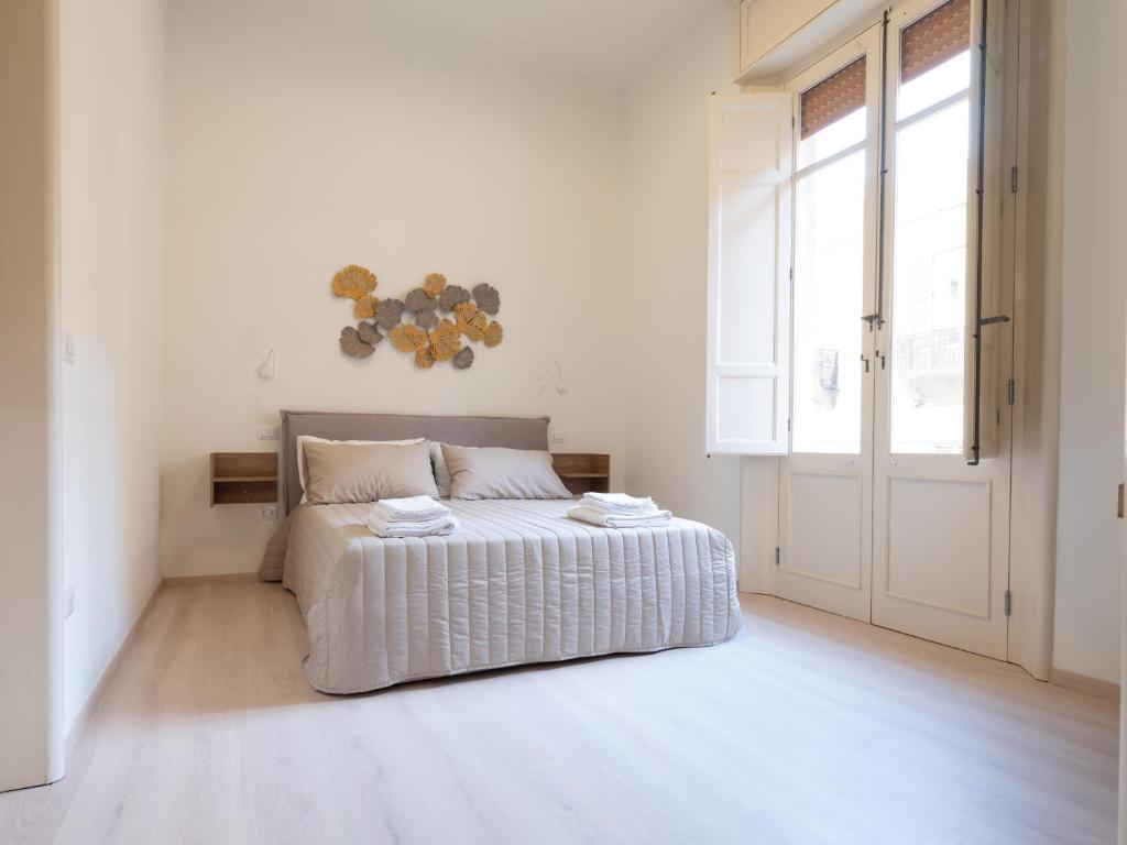 a white bedroom with a bed and a large window at MY HOUSE URBAN LUXURY B&B in Reggio Calabria