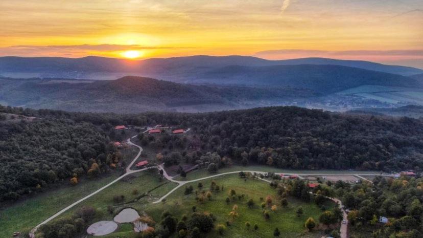 una vista aérea de un campo con la puesta de sol en las montañas en Farkaskútvölgy, en Felsőtold