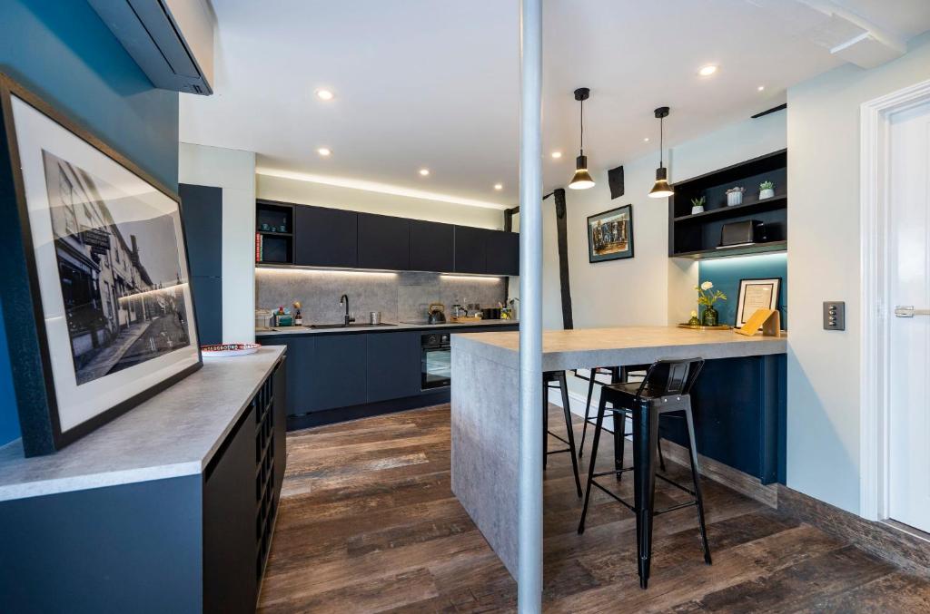 a kitchen with blue cabinets and a bar with stools at Number One High Street Clare in Sudbury