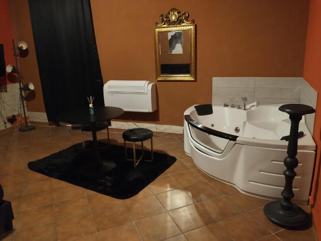 een badkamer met een bad, een tafel en een kruk bij Merope Idrosuite in Serralta