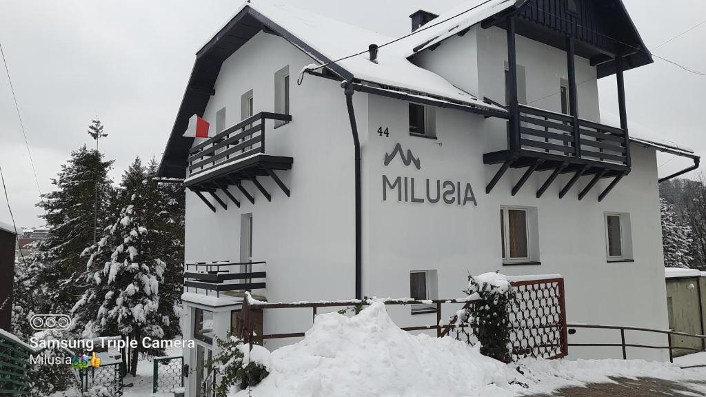 un gran edificio blanco con un cartel. en Milusia Muszyna en Muszyna