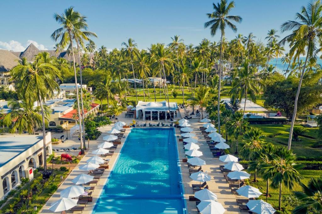 einen Luftblick auf einen Resortpool mit weißen Sonnenschirmen in der Unterkunft TUI BLUE Bahari Zanzibar in Pwani Mchangani