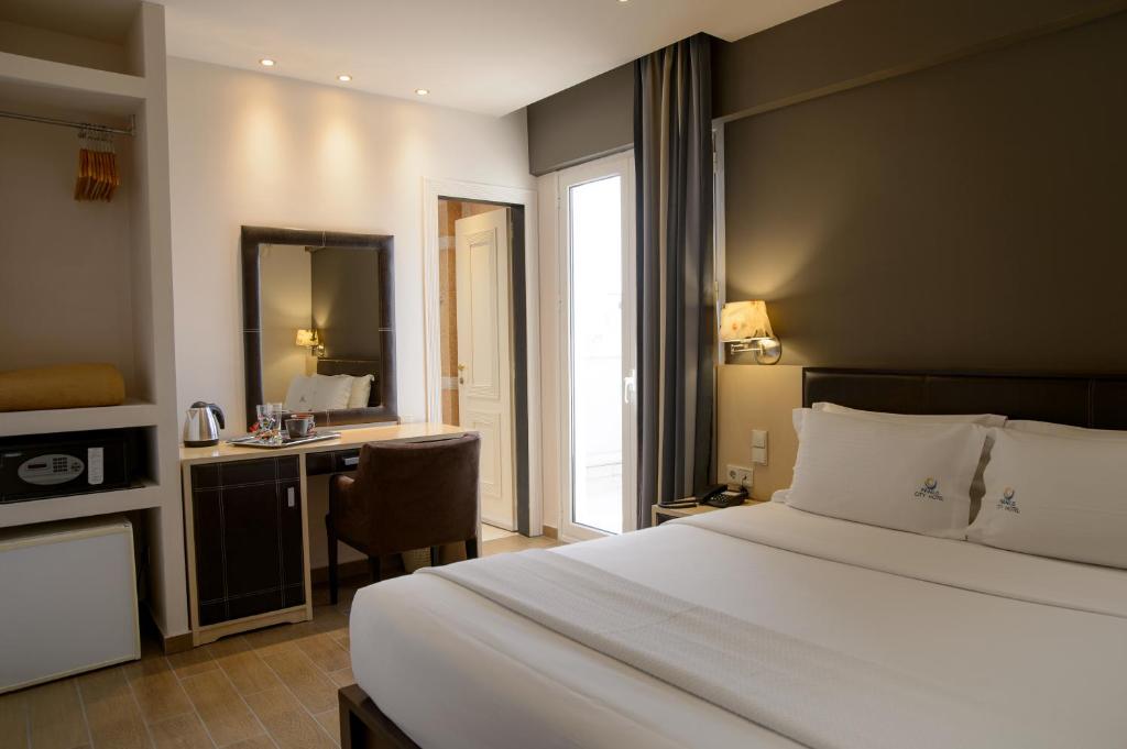 a bedroom with a bed and a desk with a mirror at Piraeus City Hotel in Piraeus