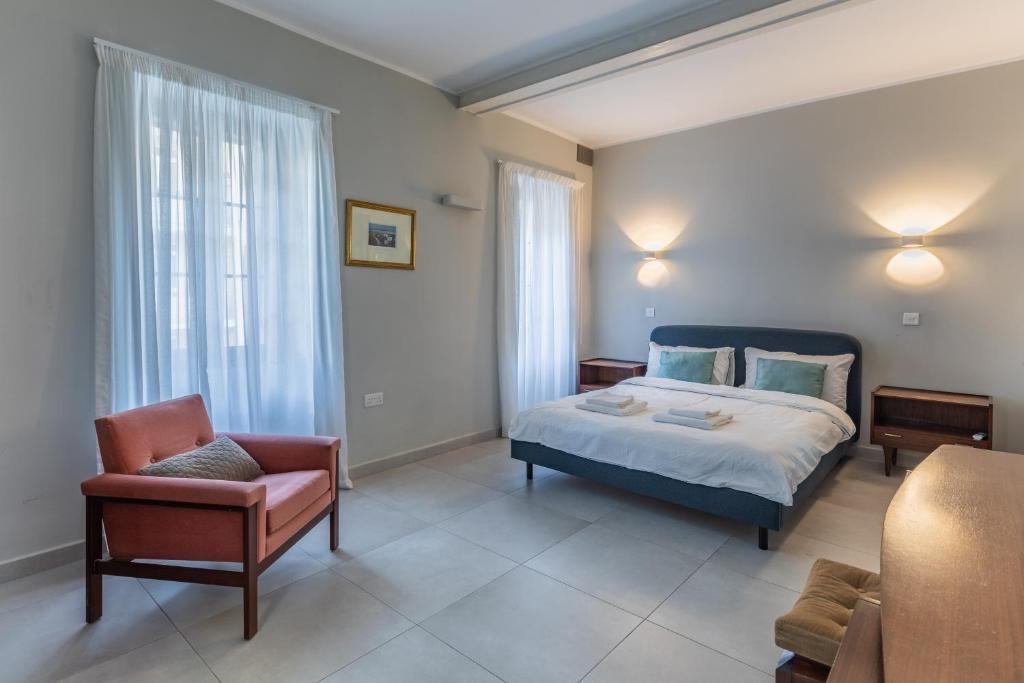 een slaapkamer met een kingsize bed en een stoel bij Stylish Retro Suites in Il-Furjana