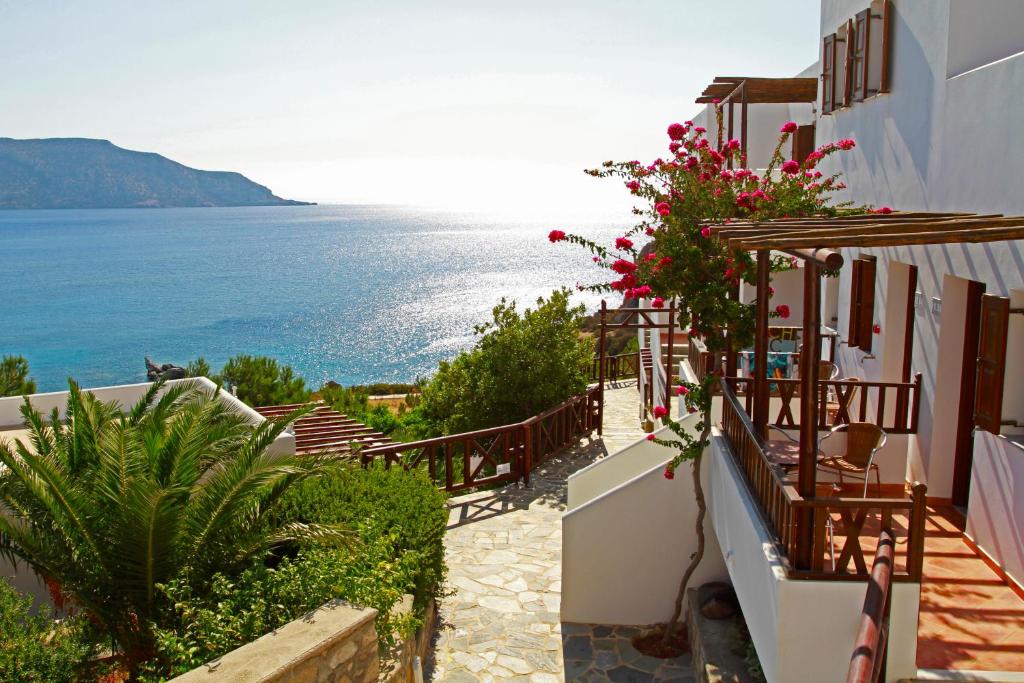 een uitzicht op de oceaan vanuit een huis met bloemen bij Aegean Village Beachfront Resort in Amoopi