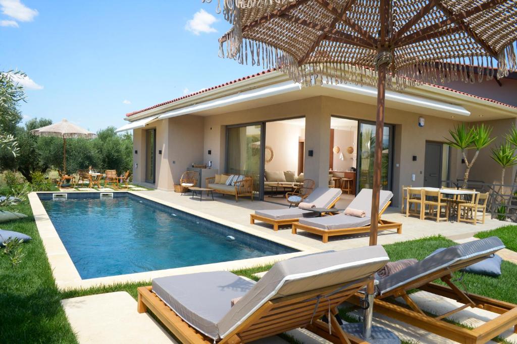 a villa with a swimming pool with chairs and an umbrella at Elaia Grove in Kalamata