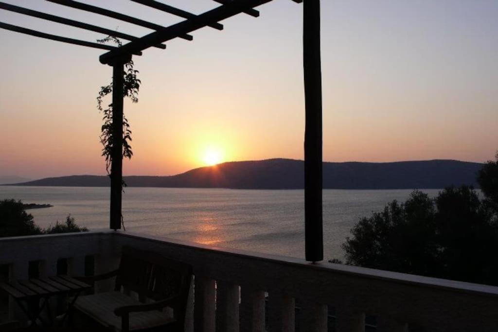 a view of a sunset from a deck with the ocean at Villa with breathtaking views and private beach in Agios Dimitrios