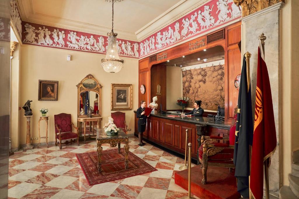 un homme debout autour d'une coiffeuse dans une pièce avec un miroir dans l'établissement Le Metropole Luxury Heritage Hotel Since 1902 by Paradise Inn Group, à Alexandrie