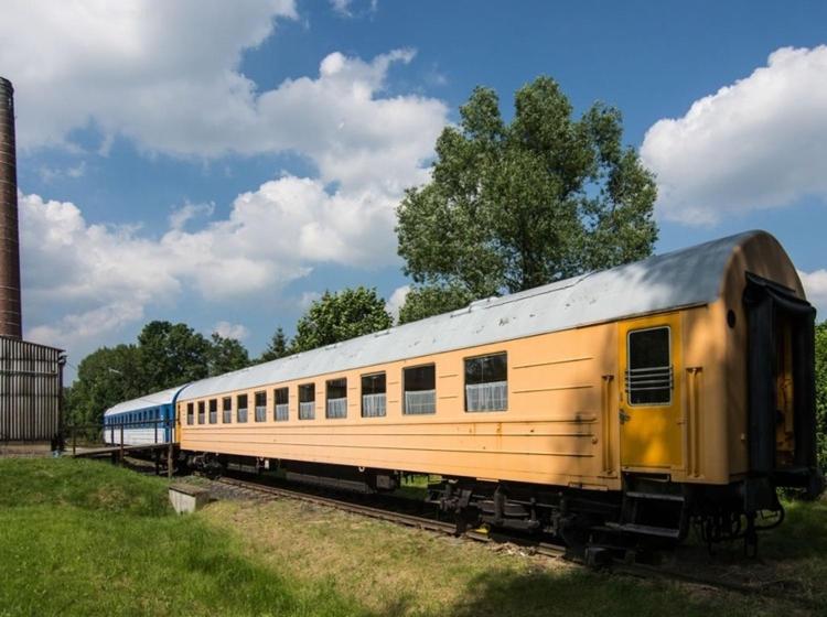 un tren amarillo está sentado en las vías en Vagónové ubytování Pivovar Kocour, en Varnsdorf