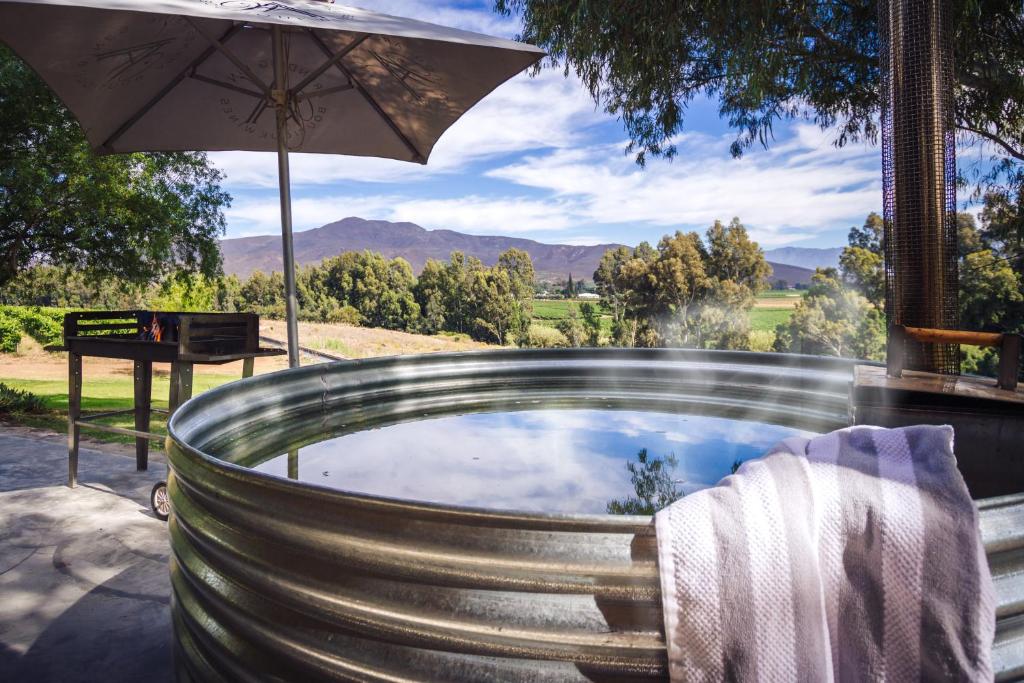 a hot tub with an umbrella on a patio at Arendsig Wine Estate & Cottages in Bonnievale