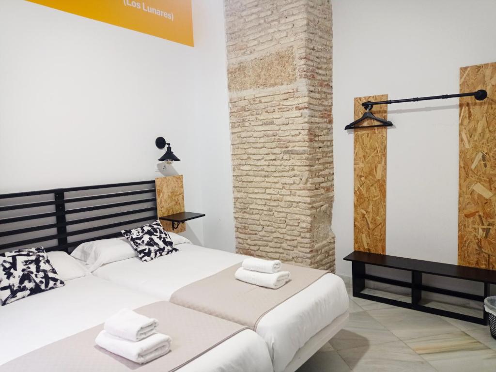 Planeta Cadiz Hostel في كاديز: غرفة نوم بسرير ابيض كبير وجدار من الطوب
