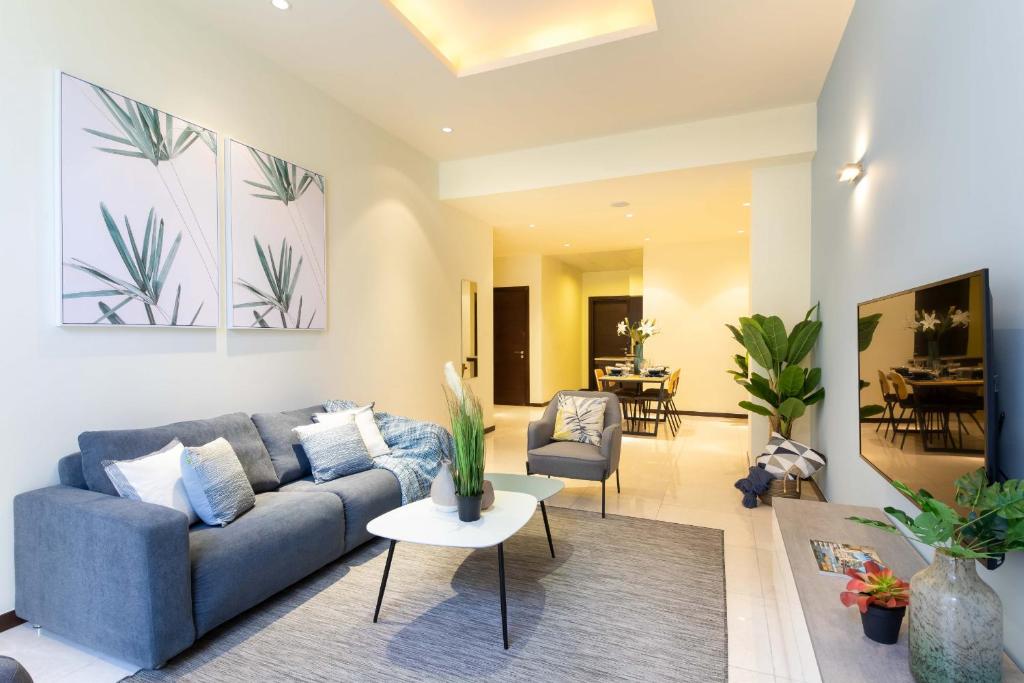 un soggiorno con divano blu e sedie di Tiara Beach Residences, Palm Jumeirah Dubai - Mint Stay a Dubai