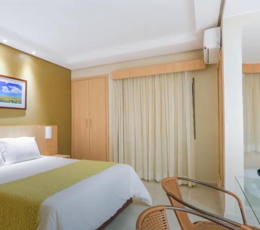 a bedroom with a bed and two chairs and a glass table at Suíte caldas novas (Risorte) in Caldas Novas