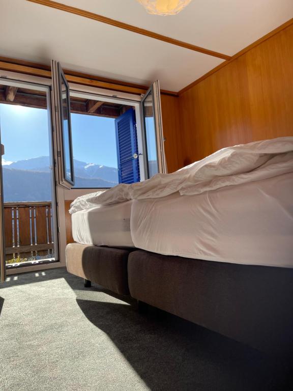 a bedroom with two beds and two windows at VISP erblick H O T E L AUSSERBERG & Late Check-in in Ausserberg