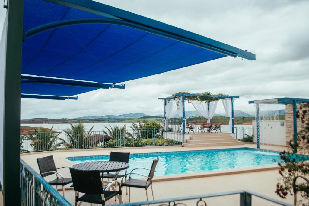 une terrasse avec une table, des chaises et une piscine dans l'établissement Casa Florida do Lago, à Guapé