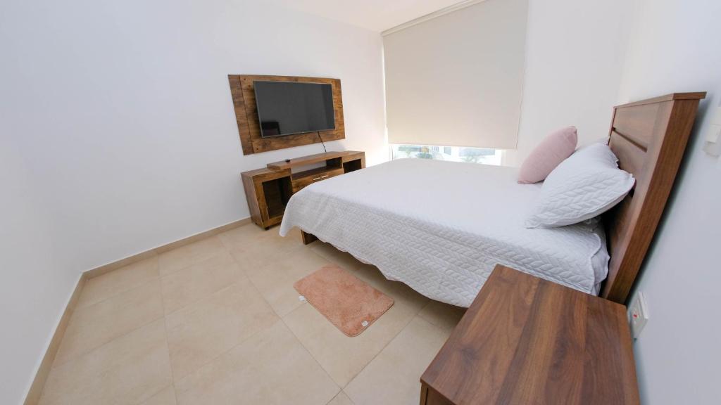Dormitorio pequeño con cama y TV en Hermosa Casa en Via Barbasquillo, en Manta