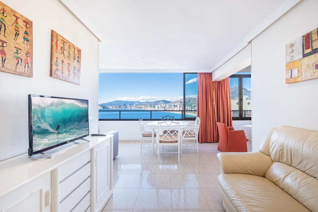 sala de estar con TV de pantalla plana y sofá en Trinisol 7-A Sea Views Apartment Levante Beach, en Benidorm