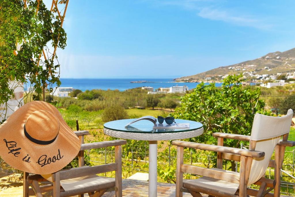 a table with a hat and two chairs with a view of the ocean at Good Life Greece Eco Villas in Posidhonía