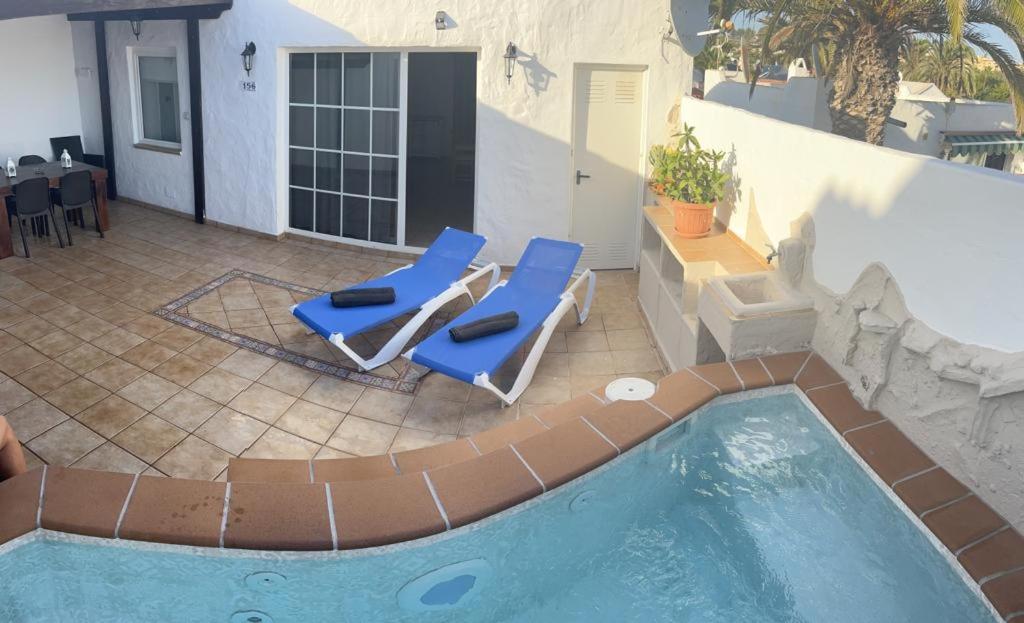 una piscina con 2 tumbonas junto a una casa en Casa Sol y Luna, en Costa Calma
