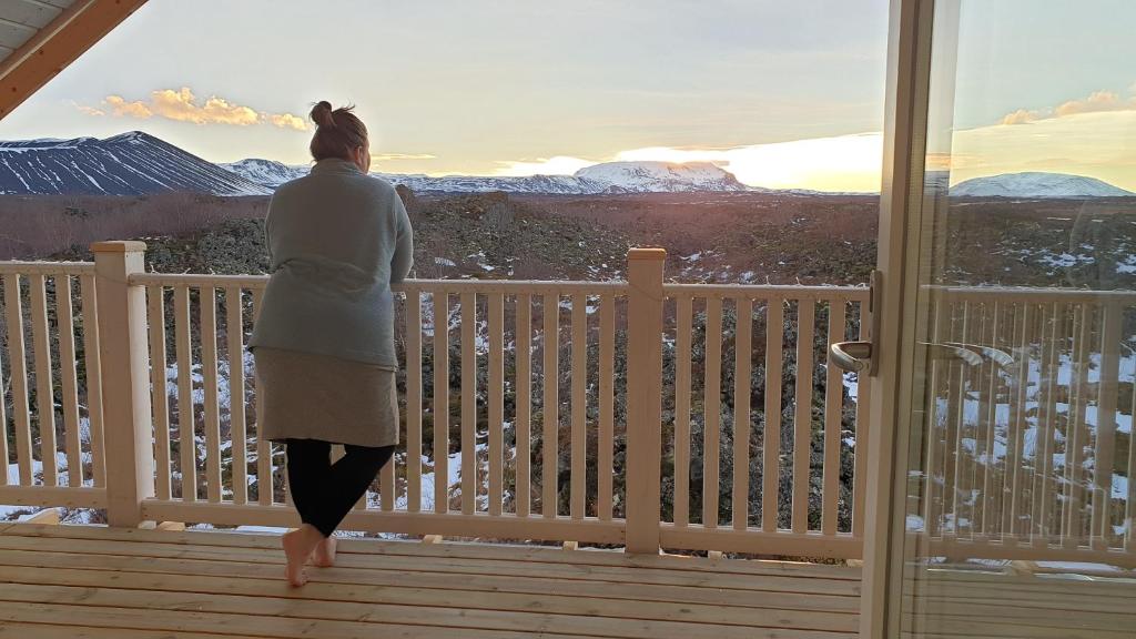 kobieta stojąca na pokładzie z widokiem na góry w obiekcie Slow Travel Mývatn - Þúfa - Private Homestay w mieście Mývatn