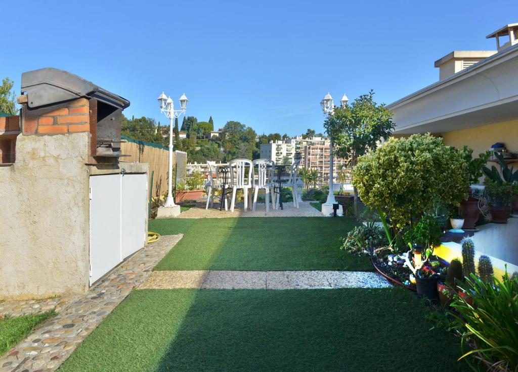 une petite arrière-cour avec de l'herbe verte et une terrasse. dans l'établissement Jardin D'Azur proche mer, à Cagnes-sur-Mer