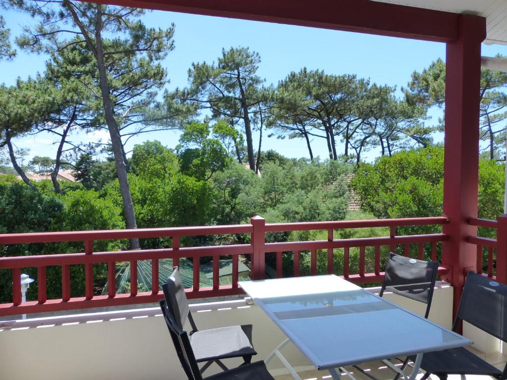 a table and chairs on a balcony with a view of trees at Appartement Pour 4 Personnes- Residence L accalmie in Capbreton