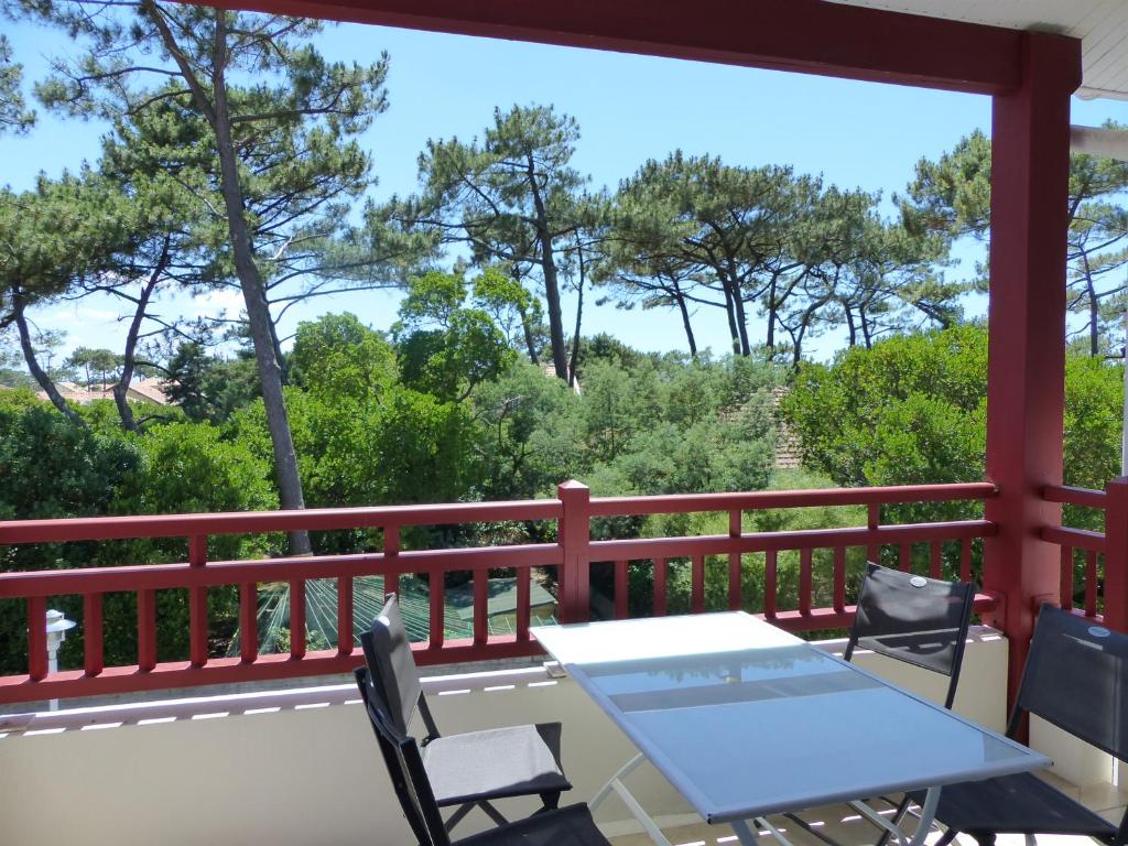 d'une table et de chaises sur un balcon avec vue sur les arbres. dans l'établissement Appartement Pour 4 Personnes- Residence L accalmie, à Capbreton
