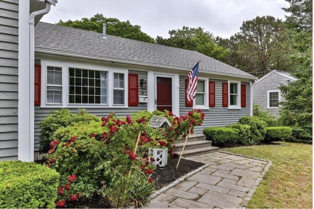 a house with a flag in the front yard at A Cozy Cape house steps to Restaurants & Beaches ~1.4 miles down scenic roads in Yarmouth
