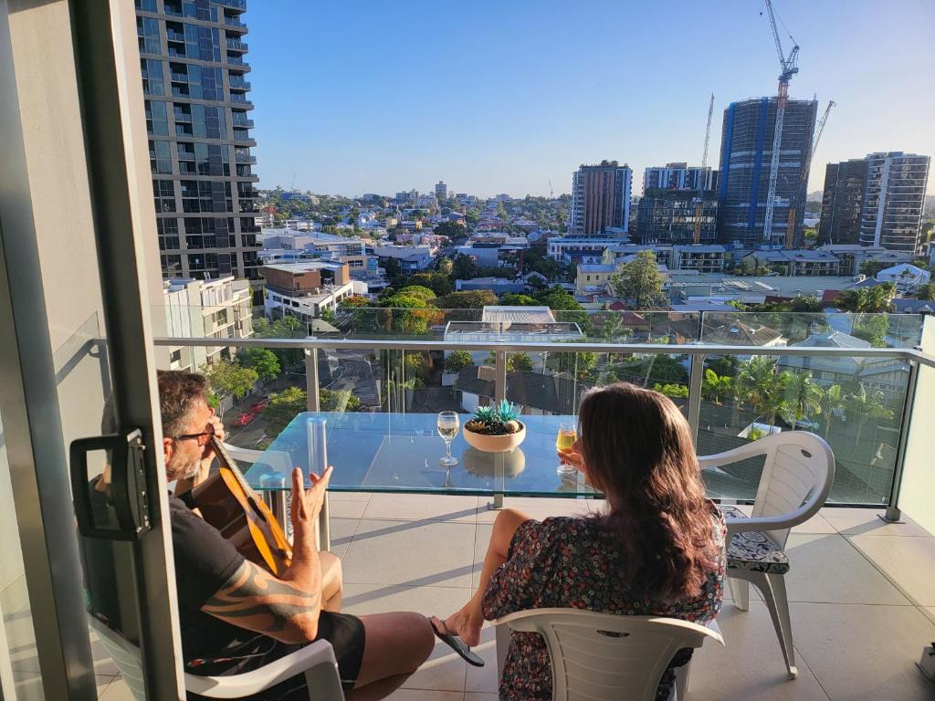 a man and woman sitting on a balcony with a guitar at Light apartment in amazing central location in Brisbane