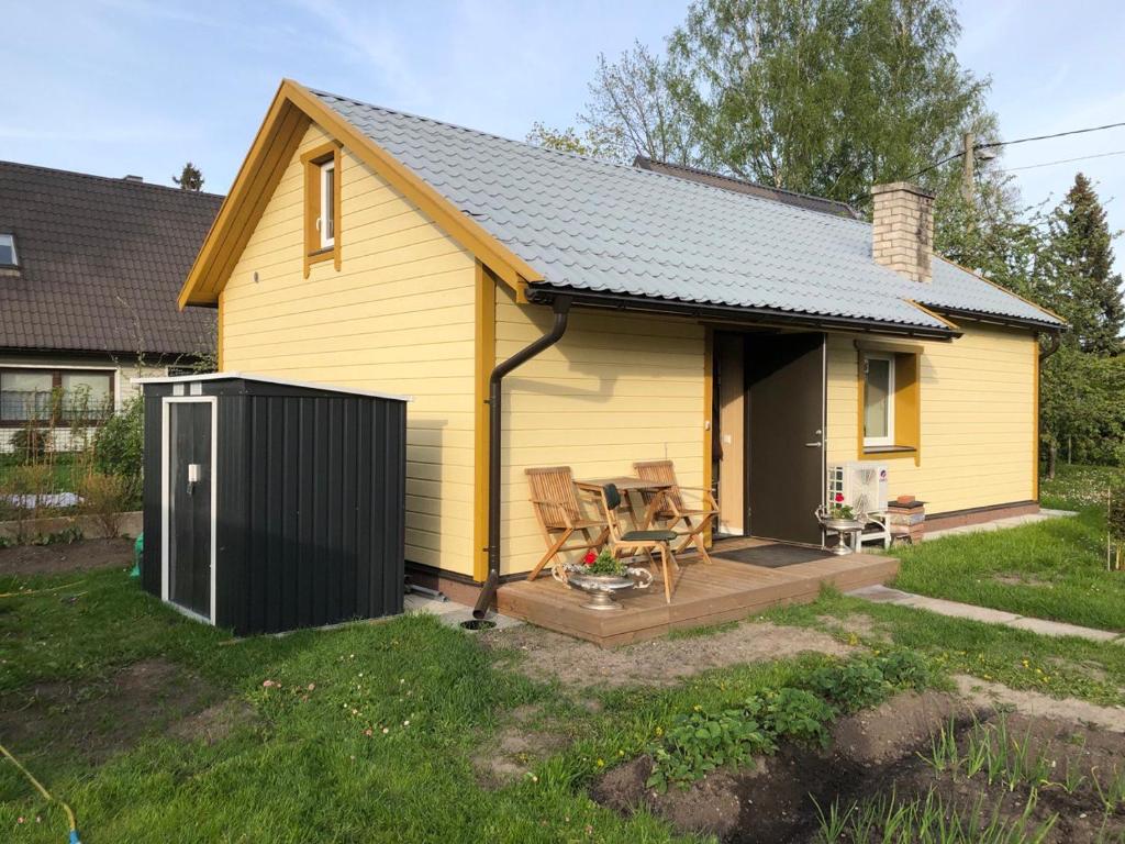 a small yellow house with a deck and a table at Uku Villa in Pärnu