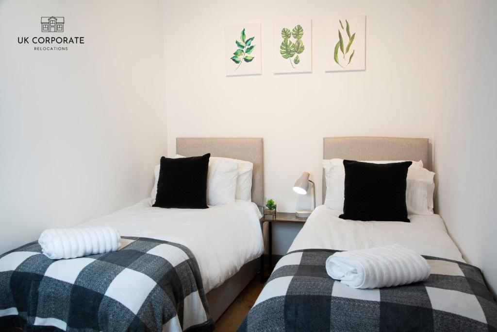 duas camas sentadas uma ao lado da outra num quarto em 2 bed Apartment by UK Corporate Relocations Ltd em Warrington