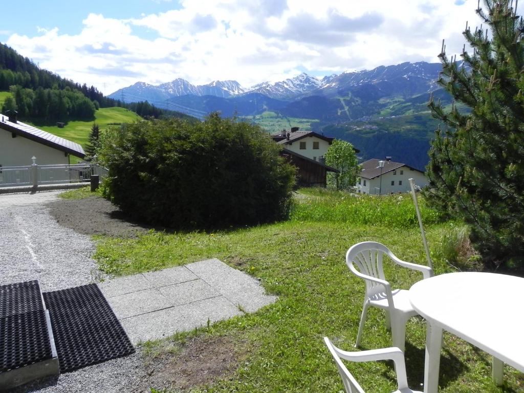 una mesa y sillas en la hierba con montañas en el fondo en Haus Edelweiss, en Fendels