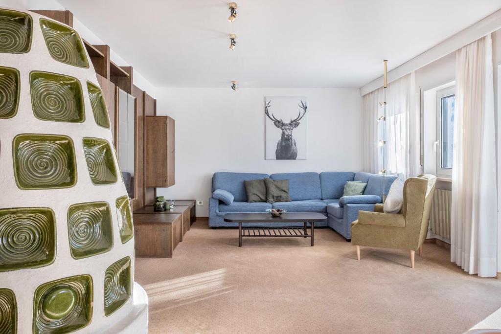 a living room with a blue couch and a chair at Sirena Carezza Apartment Regenbogen in Carezza al Lago