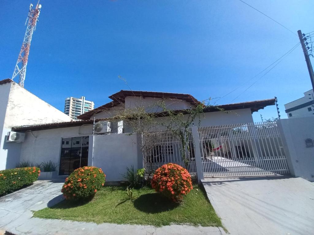 een wit huis met een hek en wat bloemen bij CASA COM PISCINA EM ÁREA NOBRE in Boa Vista
