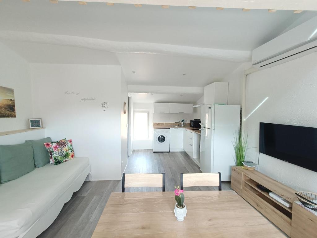 a white living room with a couch and a tv at Au centre de Fréjus Charmant appartement in Fréjus