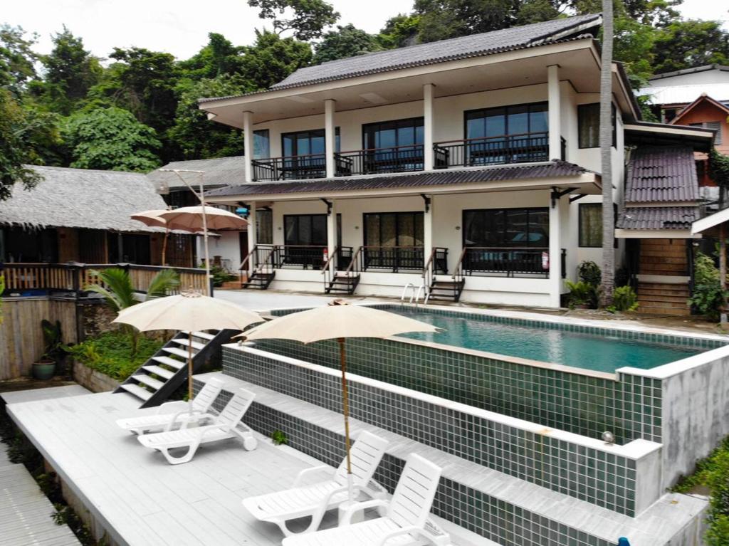 a house with a swimming pool and some chairs and umbrellas at Chunut House Resort in Phi Phi Don