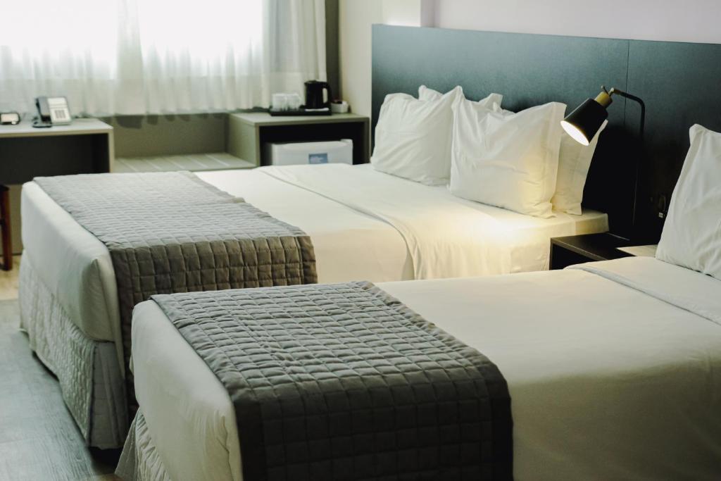 Santa Inn Hotel في باليريو كامبوريو: غرفة فندقية بسريرين مع ملاءات بيضاء