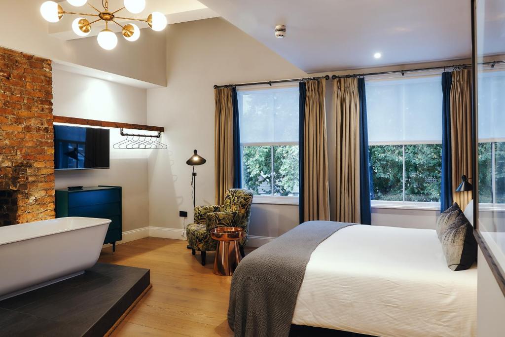 1 dormitorio con cama, bañera y ventanas en The Brownswood en Londres