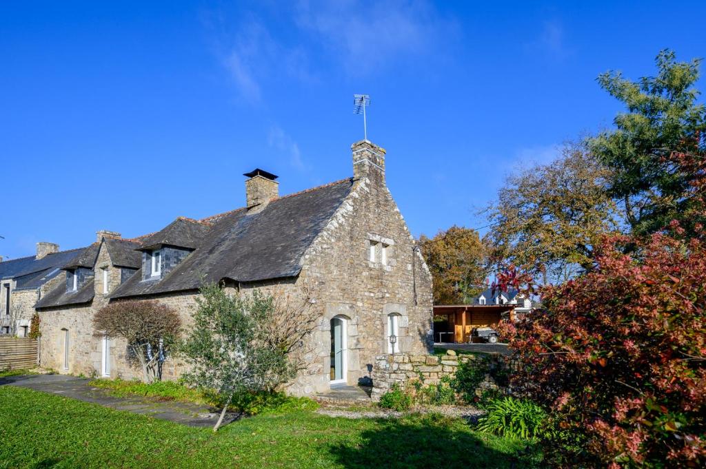 an old stone house with a black roof at Ty-Voli - Magnifique Longère rénovée in Plougoumelen
