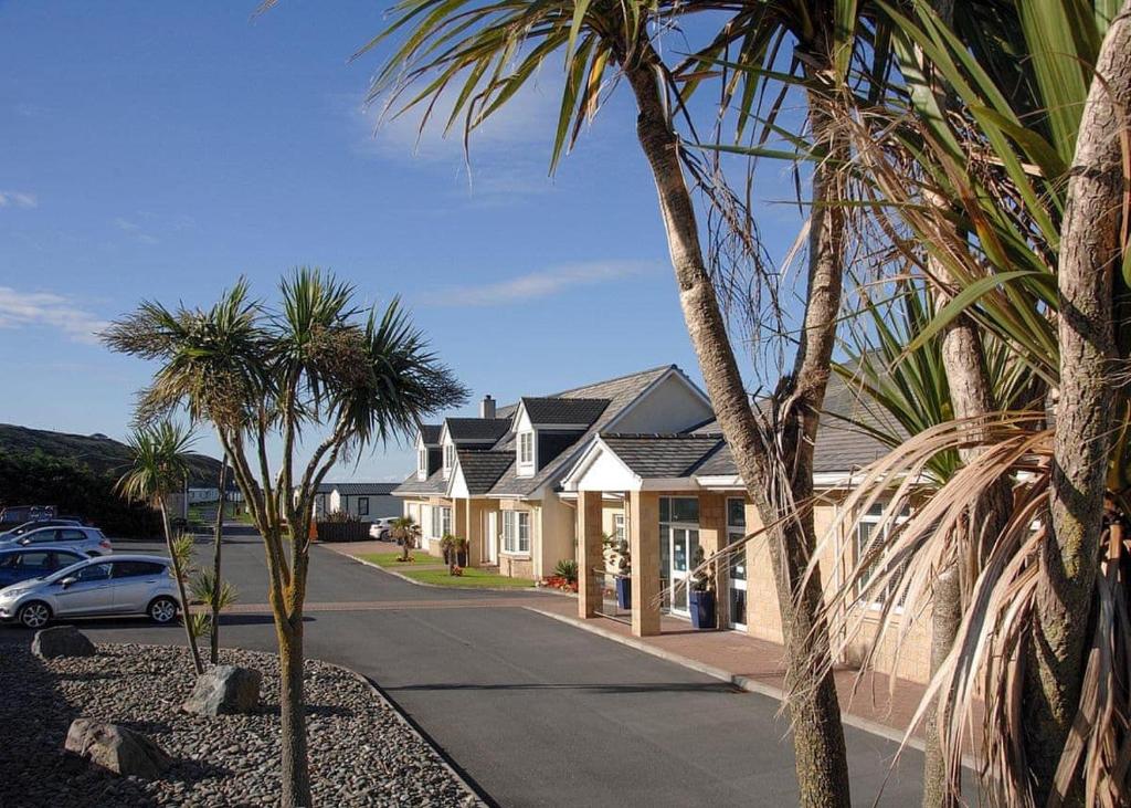 a house with palm trees in front of a street at Bennane Shore Holiday Park in Lendalfoot