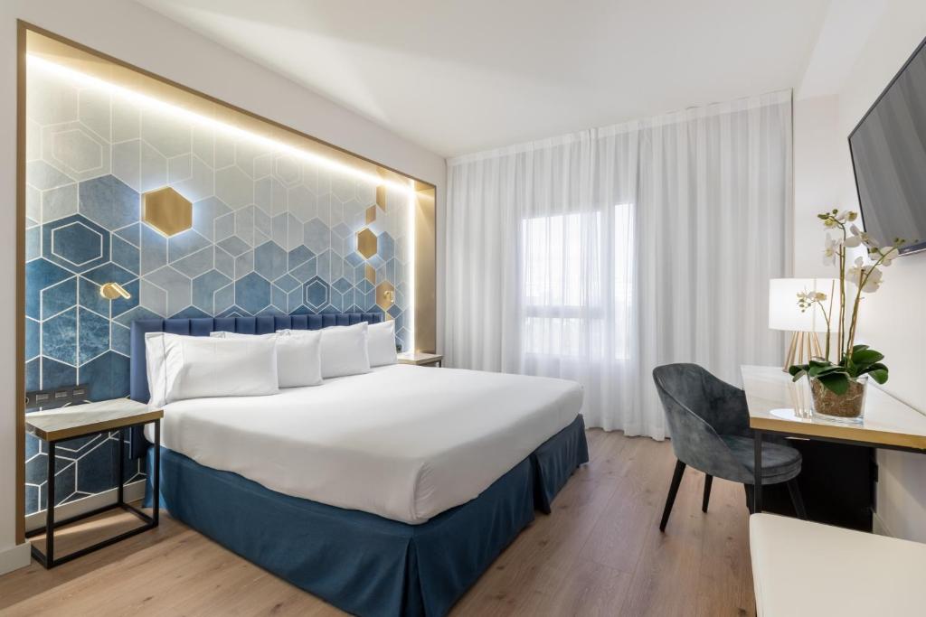 アルコベンダスにあるユーロスターズ グラン マドリードのベッドとデスクが備わるホテルルームです。