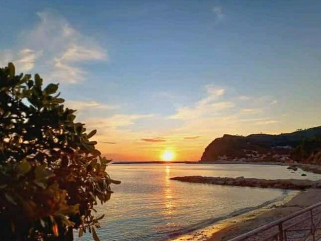 una puesta de sol sobre un cuerpo de agua con una playa en Due passi dal mare, en Montecorice