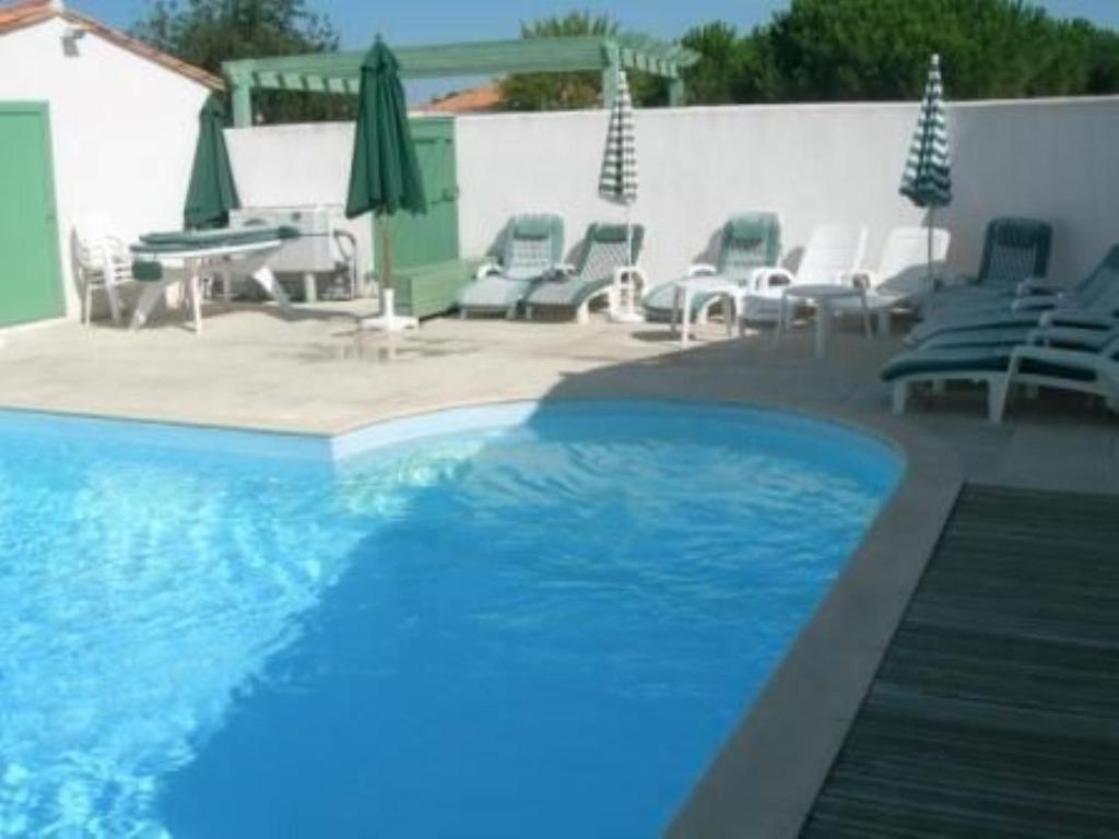 a swimming pool with chairs and umbrellas and a table at Charmante maison avec piscine partagee in Le Bois-Plage-en-Ré