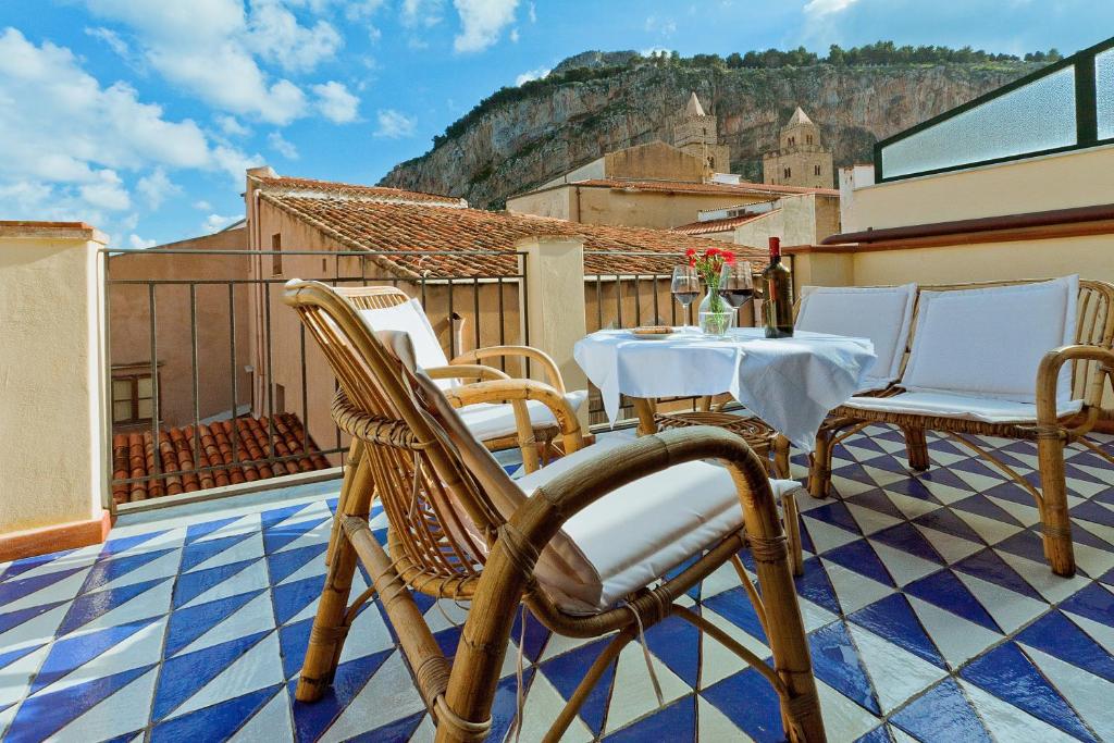 een patio met een tafel en stoelen op een balkon bij Hotel La Plumeria in Cefalù