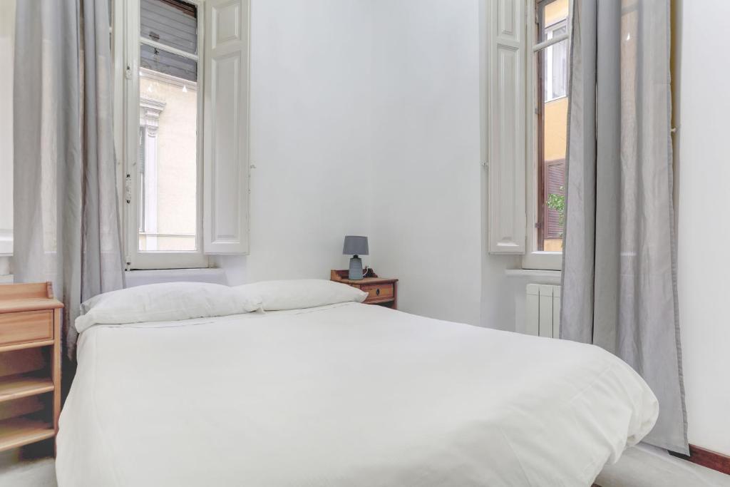 een witte slaapkamer met een bed en 2 ramen bij Charming Colosseum in Rome