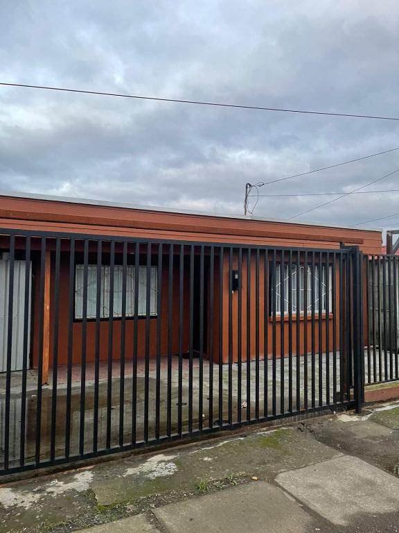 un edificio rojo con una valla negra delante de él en Casa amoblada en Coronel, en Concepción