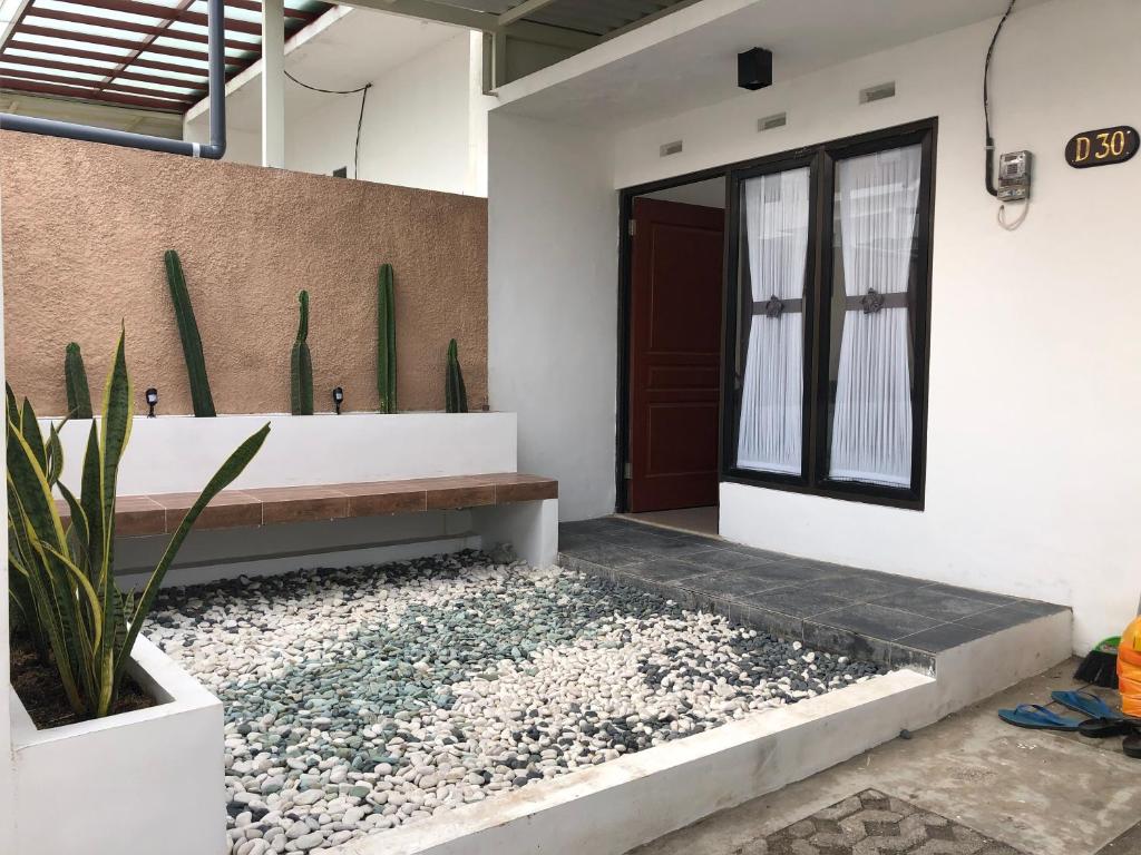 uma entrada da casa com um banco e um jardim de pedras em Homestay Syariah Orchard Family D30 em Sengkaling