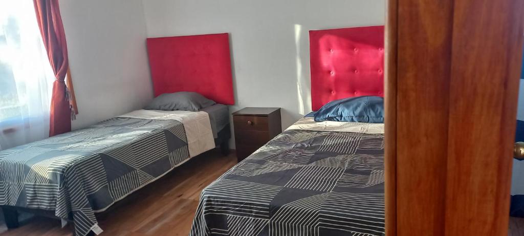 a bedroom with two beds and a red headboard at Piscinas y cabañas san antonio in Los Ángeles