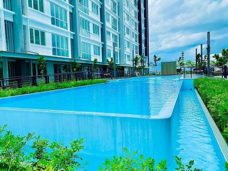a blue swimming pool in front of a building at SiX Staycation in Kuching