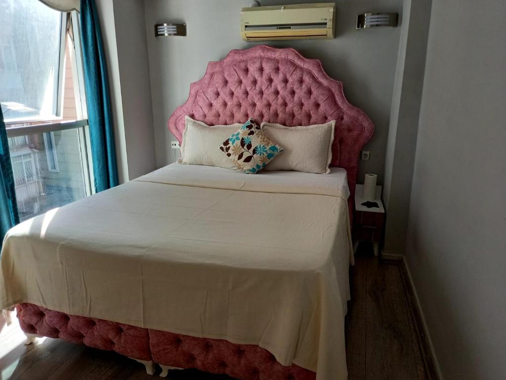 a pink bed with a large headboard in a room at Invivo Hotel in İzmir